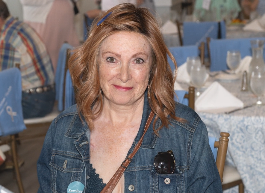 Woman soft smiling in a jean jacket at an event.
